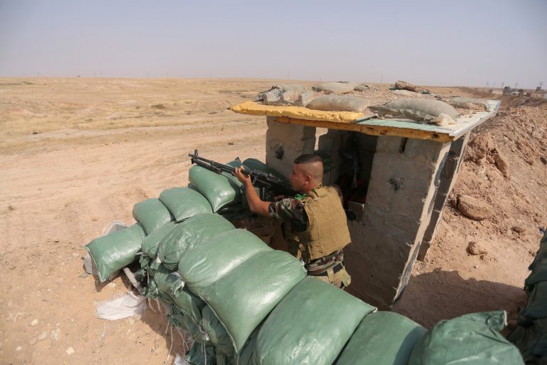 In this Thursday, Oct. 2, 2014 photo, an Iraqi Shiite militiamen takes cover after clashes with militants from the Islamic State group, near Qara Tappa, about 75 miles northeast of Baghdad in Iraq's Diyala province. (AP Photo/Jaber al-Helo)