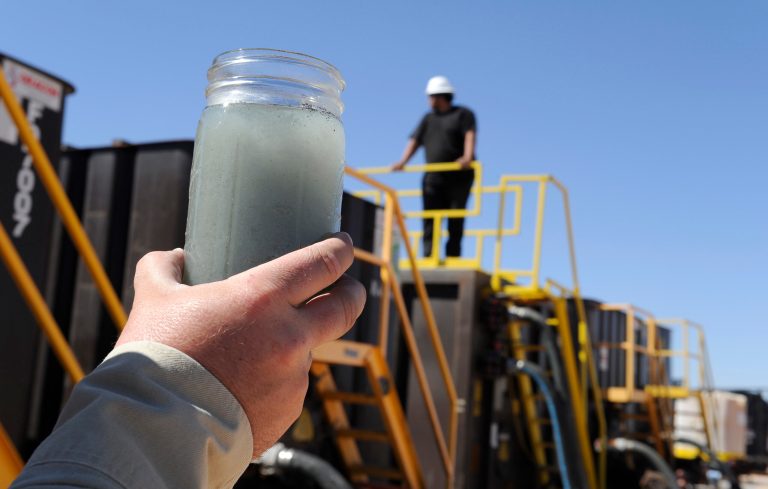 A jar holding waste water from hydraulic fracturing is held up to the light at a recycling site in Midland, Texas. (AP/Pat Sullivan)
