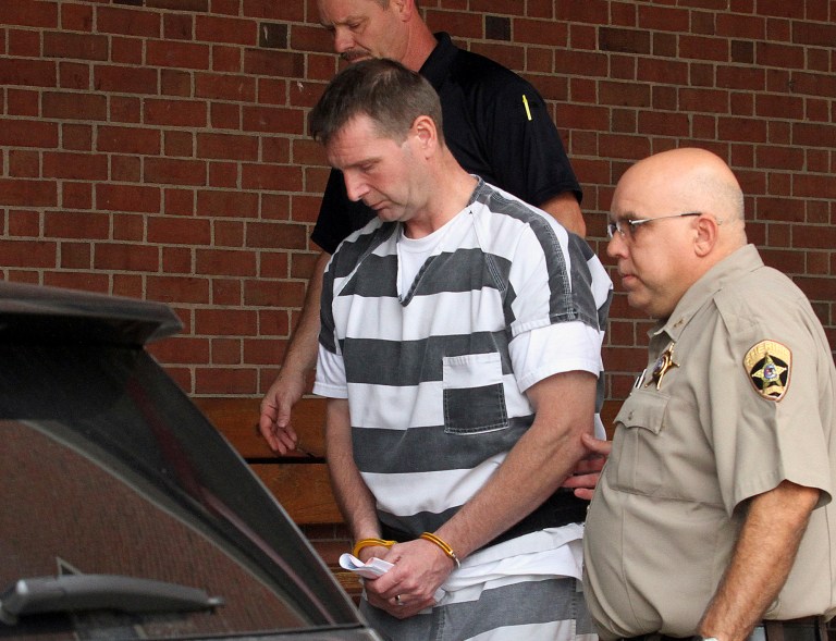 FILE - In this Aug. 28, 2014 file photo, Curtis Lovelace, 45, is escorted out of the Adams County Courthouse in Quincy, Ill., after being formally charged with first-degree murder in the February 2006 death of his first wife, 38-year-old Cory Lovelace. Newly released transcripts from a coroner's inquest in March 2006, five weeks after Lovelace's death, detail what an investigator said was the account by her husband of what happened in the Adams County house in the moments before and after Cory Lovelace died there. (AP Photo/The Quincy Herald-Whig, Steve Bohnstedt, File)