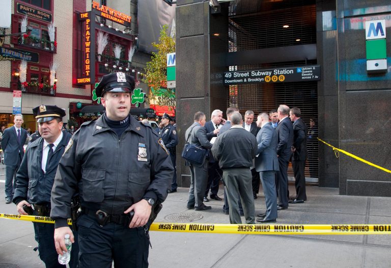   Uniformed and plainclothes police officers stand outside a New York subway station after a man was killed after falling into the path of a train, Monday, Dec. 3, 2012. Transit officials say police are investigating whether he could have been pushed onto the tracks. (AP Photo/Mark Lennihan)  