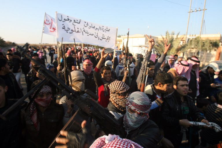 Gunmen gather in a street as they chant slogans against Iraq's Shiite-led government and demand that the Iraqi army not try to enter the city in Fallujah, 40 miles west of Baghdad. Fierce clashes erupted between Iraqi special forces and al Qaeda-linked militants outside the city of Fallujah, a flare-up in a days-long standoff in the Sunni-dominated western province of Anbar, Iraqi officials said. The banner in Arabic reads, 