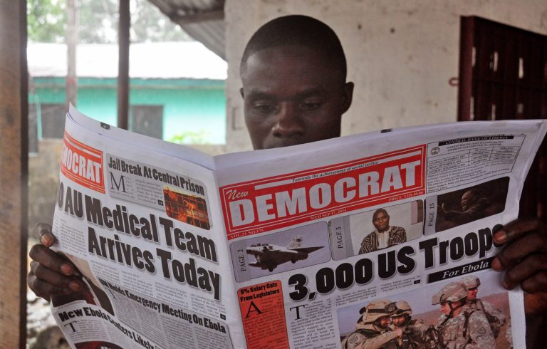 A man reads a news paper with headlines comment on American President Barrack Obama announcement on sending troops to fight the Ebola virus in Monrovia, Liberia, Wednesday, Sept. 17, 2014. Liberia's president called Wednesday on the world to do more to end a spiraling Ebola outbreak, saying 