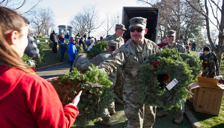 Members of the U.S. Army hand-out wreaths to volunteers as they place remembrance wreaths on the nearly 245,000 headstones at Arlington National Cemetery. (AP Photo/Cliff Owen)