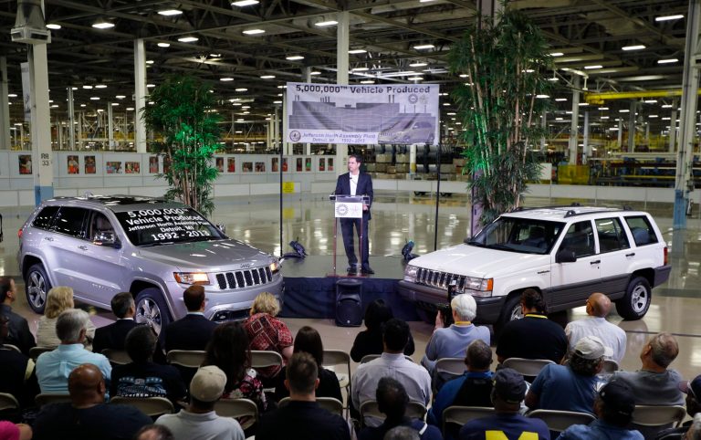   FILE - In this , Tuesday, Aug. 13, 2013, file photo, Scott Garberding, senior vice president of manufacturing for Chrysler Group LLC stands between a 1992 Grand Cherokee, right, and the automaker's 5,000,000th vehicle produced at the Jefferson North Assembly Plant, in Detroit. The Federal Reserve reports on output from U.S. factories, mines and utilities in August on Monday, Sept. 16, 2013. (AP Photo/Carlos Osorio)  