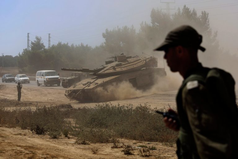 An Israeli army officer walks near a Merkava tank as it advances towards the Israel Gaza border Gaza Strip, Friday, Aug. 1, 2014. (AP Photo/Tsafrir Abayov)