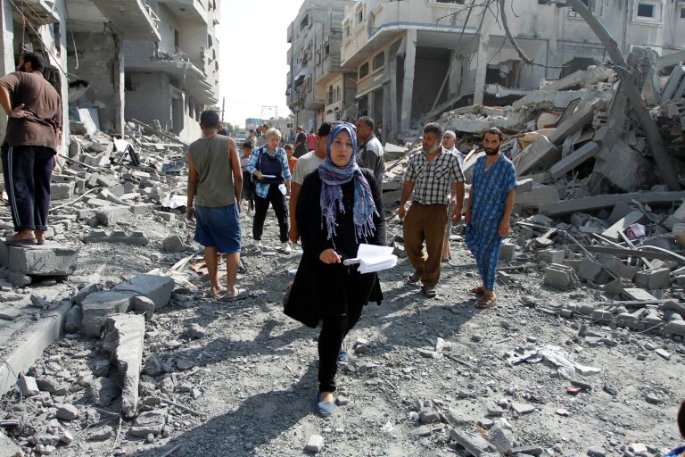 In this Saturday, Aug. 2, 2014 photo, Sabreen el-Tartour, of the Palestinian Center for Human Rights, walks through a devastated area in Gaza City. From the first day of Israel-Hamas fighting on July 8, human rights groups operating in Gaza have been collecting detailed information about the aftermath of Israeli strikes, so far more than 4,600, according to the military, to lay the groundwork for future legal proceedings. (AP Photo/Dusan Vranic)