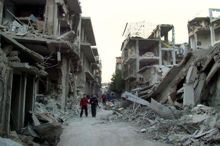 File-This file photo released on Thursday Nov. 29, 2012 by the anti-government activist group Homs City Union of The Syrian Revolution, which has been authenticated based on its contents and other AP reporting, Syrian citizens walk in a destroyed street that was attacked by Syrian forces warplanes, at Abu al-Hol street in Homs province, Syria. Rebels make their last stand in Homs, fighting desperately to cling to their last bastion in the city's old quarters as emboldened forces loyal to President Bashar Assad launch a fierce assault to evict them completely from the city once known as the capital of the revolution. (AP Photo/Homs City Union of The Syrian Revolution, File)