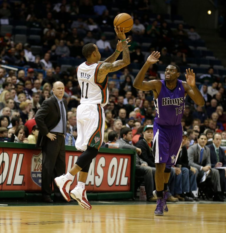   Milwaukee Bucks' Monta Ellis (11) hits a half-court shot at the end of the first quarter as Sacramento Kings' Tyreke Evans(13) defends during a NBA basketball game on Wednesday, Dec. 12, 2012, in Milwaukee. Bucks head coach Scott Skiles, left, watches the play. (AP Photo/Jeffrey Phelps)  