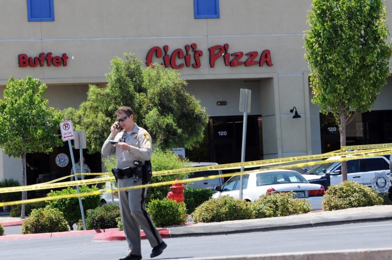 A Las Vegas police officer walks near the scene of a shooting in Las Vegas, Sunday, June 8, 2014. The spree began around 11:30 a.m. Sunday when a man and woman walked into CiCi's Pizza and shot two officers who were eating lunch, Las Vegas police spokesman Larry Hadfield said. (AP Photo/Las Vegas Review-Journal, Eric Verduzco)