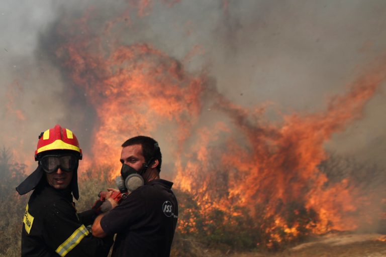   Firefighters try to extinguish a fire near the town of Palea Fokaia, south of Athens, Saturday, June 16, 2012. A fire aided by strong winds has burned grassland and threatened houses near the town of Keratea, 50 kilometers (30 miles) south of Athens. The fire started in the early Saturday afternoon on dried grass, apparently as the result of an accident and has been spreading fast, threatening to engulf isolated houses on the outskirts of the towns of Keratea and Palea Fokaia. (AP Photo/Kostas Tsironis)  