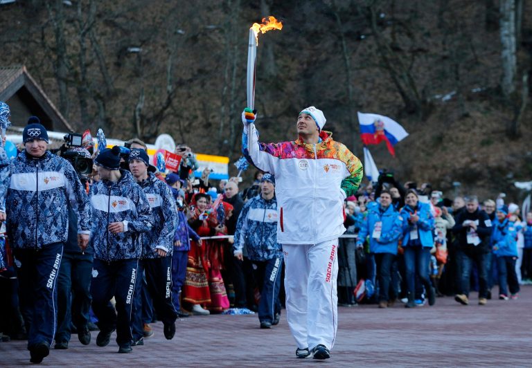 Alexey Voyevoda, a former Olympic bobsledder, who won silver in the 4-man bobsled in Turin in 2006, carries the Olympic torch as it makes it's way throughout the streets of the Rosa Khutor ski resort in Krasnaya Polyana, Russia at the Sochi 2014 Winter Olympics, Wednesday, Feb. 5, 2014.  (AP Photo/Christophe Ena)