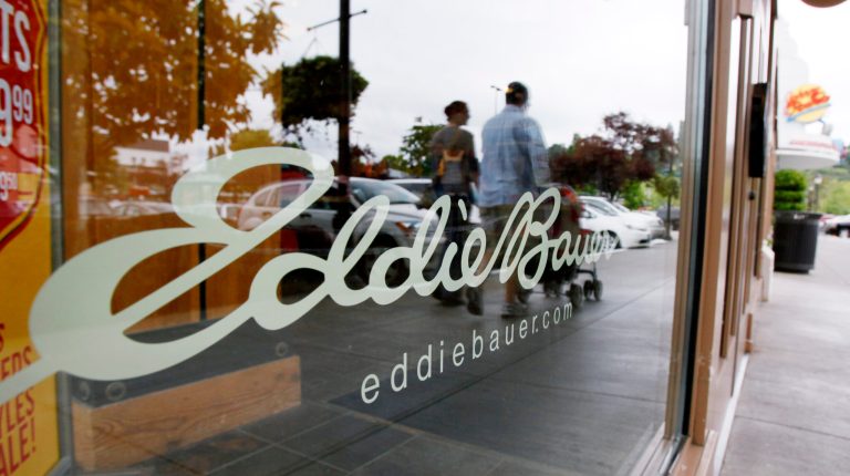 FILE - In this Wednesday, June 17, 2009, file photo, shoppers are reflected in the window as they walk past an Eddie Bauer store, in Seattle. Jos. A. Bank Clothiers Inc. said Friday, Feb. 14. 2014, it is buying the parent company of Eddie Bauer in a cash-and-stock deal valued at $825 million that will help strengthen its men's wear business and diversify its offerings. (AP Photo/Elaine Thompson, File)