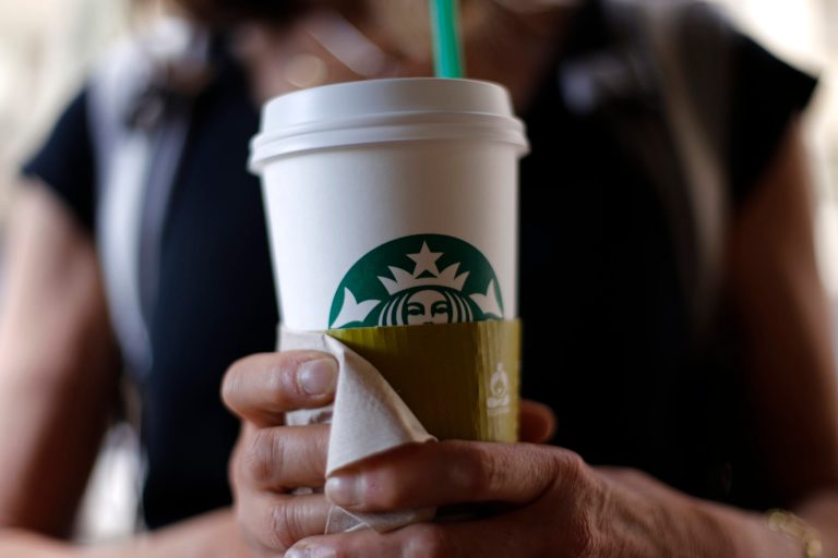 In this May 31, 2014 photo, a woman holds a coffee drink outside a Starbucks in downtown Chicago. Starbucks is raising prices on some of its drinks by 5 cents to 20 cents starting next week, and customers can also soon expect to pay $1 more for the packaged coffee it sells in supermarkets. Prices for medium and large brewed coffees, which are known as Grande and Venti, respectively, will go up between 10 cents and 15 cents in most U.S. markets, the company said.  (AP Photo/Gene J. Puskar)
