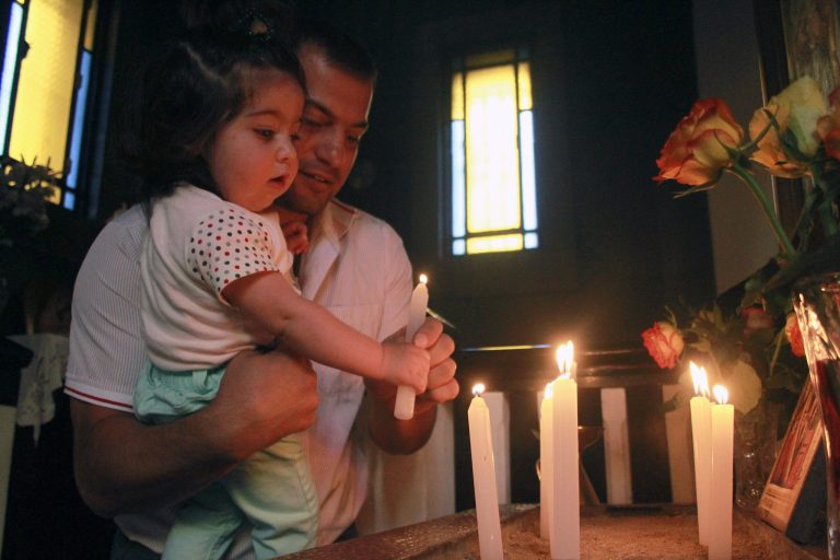 In this Sunday June 1, 2014 photo, Armen Madatyan and his 1 year-old daughter Stella light a candle at the church in Addis Ababa, Ethiopia. There is a small handful of people keeping the Armenian community in Ethiopia alive. Despite a fall in numbers from a peak of 1,200 in the 1960s to less than 100 people today, the Armenian school, church and social club still open their doors. (AP Photo/Elias Asmare)