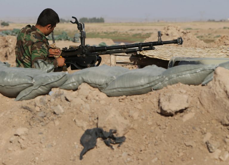 In this picture taken on Monday, June 30, 2014, a Kurdish Peshmerga fighter cleans his weapon on his position behind a dirt barrier built along the front line with militants from the al-Qaida-inspired Islamic State of Iraq and the Levant (ISIL), in Mariam Bek village, between the northern cities of Tikrit and Kirkuk, Iraq. Demonstrating their growing independence from the rest of Iraq, the largely-autonomous Kurdish regional government is setting up dirt barriers that they hope will ultimately set the borders of their future state. (AP Photo/Hussein Malla)