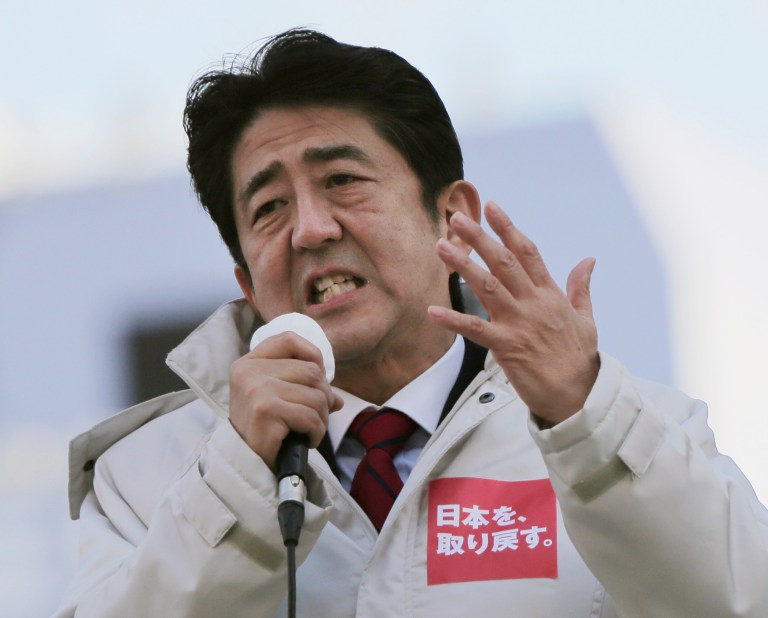   In this Tuesday, Dec. 11, 2012 photo, Japan's main opposition Liberal Democratic Party (LDP) President Shinzo Abe speaks during a campaign rally for the Dec. 16 parliamentary elections in Machida, on the outskirts of Tokyo. Former Prime Minister Abe, who is poised to head the government again if his LDP does as well most polls are forecasting, favors forcing the central bank to do whatever it takes to meet an inflation target, of perhaps 2 percent, to break the economy out of its deflationary funk. The party slogan on his jacket read: We get back Japan. (AP Photo/Itsuo Inouye)  