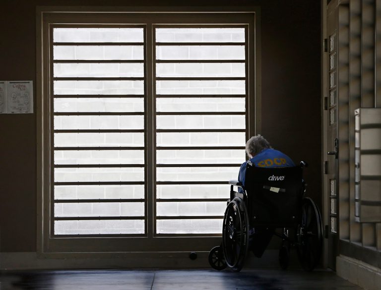 In this Thursday, July 24, 2014 photo, an inmate sits by a window at the mental health unit at the California Department of Corrections and Rehabilitation's Stockton Health Facility in Stockton, Calif. The California Association of Psychiatric Technicians union says that employees at the facility were instructed to routinely falsify suicide watch records, endangering inmates and violating standards imposed in response to federal court orders. The union claims inadequate staffing is prompting shortcuts that circumvent requirements meant to protect inmates. (AP Photo/Rich Pedroncelli)