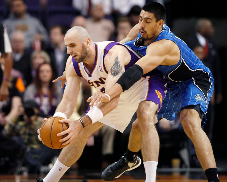   Phoenix Suns center Marcin Gortat, left, of Poland, maintains possession of the ball as Orlando Magic center Gustavo Ayon, right, of Mexico, attempts a steal in the first quarter of an NBA basketball game, Sunday, Dec. 9, 2012, in Phoenix. (AP Photo/Paul Connors)  