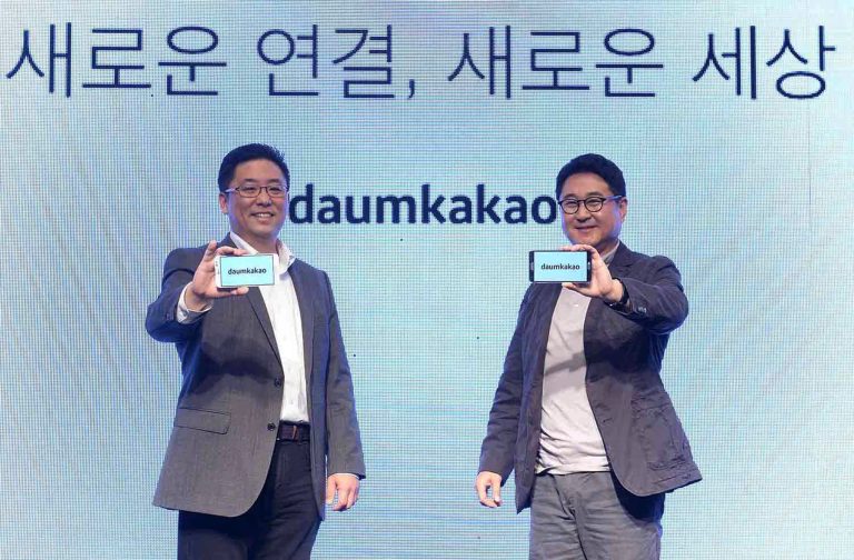 In this Oct. 1, 2014 photo released by Daum Kakao, Saehoon Choi, left, and Sirgoo Lee, the two co-CEOs of Daum Kakao, show their company's new logo during the Daum Kakao launch press conference in Seoul, South Korea. The letters at back ground read 