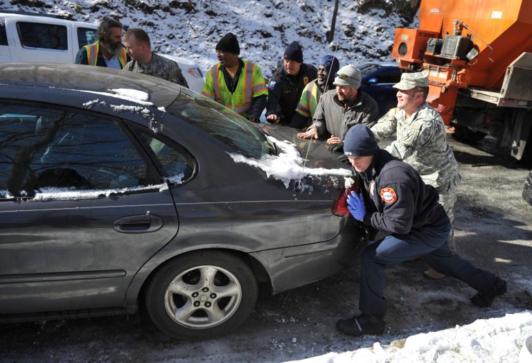 Contractors, volunteers and members of the Georgia National Guard help move a car that was blocking the road, in Atlanta on Thursday. (AP Photo/Atlanta Journal-Constitution, Brant Sanderlin)