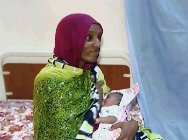 FILE - In this file image made from an undated video provided Thursday, June 5, 2014, by Al Fajer, a Sudanese nongovernmental organization, Meriam Ibrahim breastfeeds her newborn baby girl that she gave birth to in jail last week, as the NGO visits her in a room at a prison in Khartoum, Sudan. A Sudanese Christian woman whose death sentence for apostasy was overturned was freed again on Thursday, June 26, 2014, after being detained on accusations of forging travel documents. (AP Photo/Al Fajer, File)