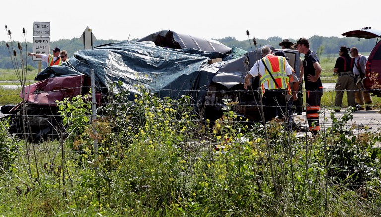 In this Monday, July 21, 2014 photo, emergency personnel use tarps to cover two vehicles while investigating an accident that killed four people on Interstate 55 near Channahon, Ill., southwest of Chicago. On Tuesday, July 22, semi-truck driver Francisco Espinal Quiroz, 51, of Leesburg, Ind., who was involved in the crash, was charged with failure to reduce speed to prevent an accident and willfully making false entries in his logbook. (AP Photo/The Herald-News, Rob Winner)  MANDATORY CREDIT
