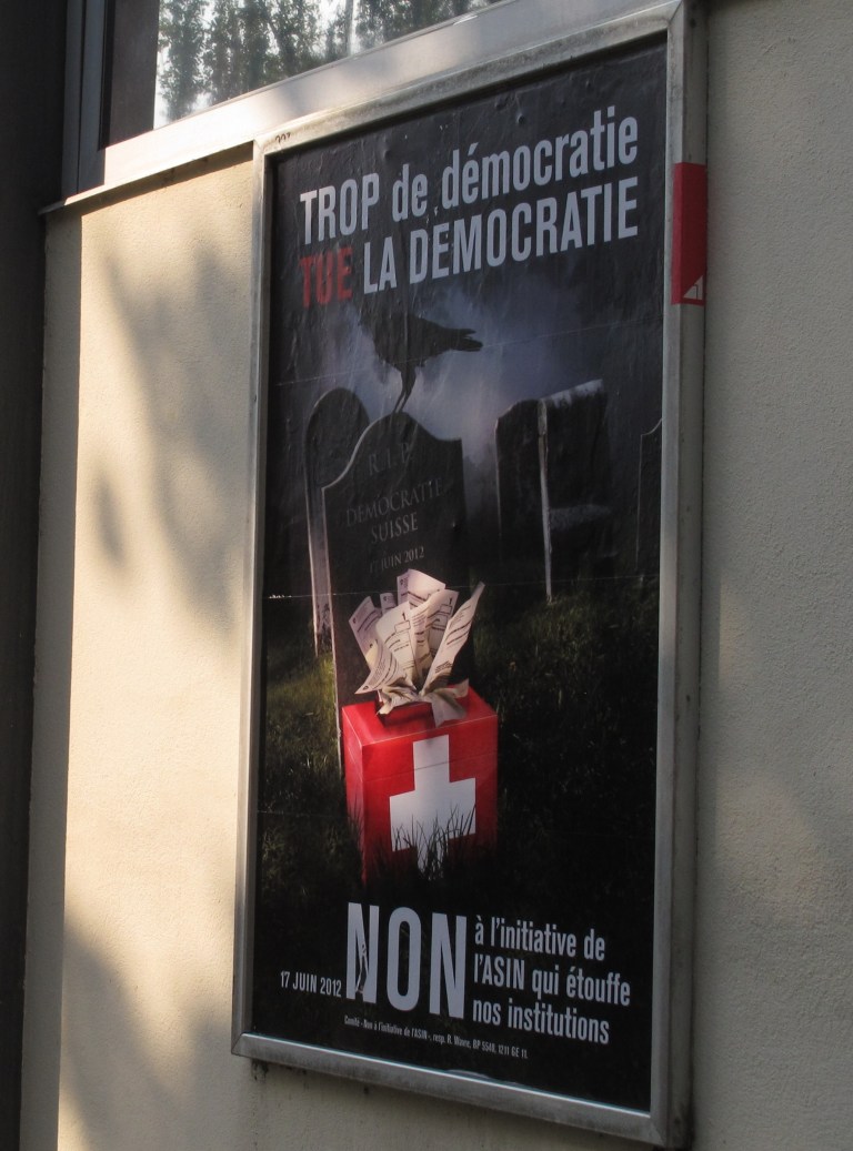   FILE - In this picture taken May 24, 2012 a poster, right, seen in Geneva, Switzerland, urging Swiss voters to reject a proposal to automatically hold a referendum whenever the government signs an important international treaty. Experts say the proposal by a nationalist group has little chance of passing in a nationwide ballot Sunday but if it did, it would severely curtail the government's power to negotiate treaties .Poster reads . Too much Democracy kills Democracy, and at bottom : No. (AP Photo/Frank Jordans)  