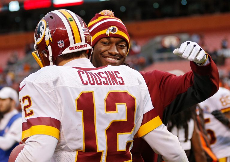 Injured Washington Redskins quarterback Robert Griffin III, right, hugs Kirk Cousins (12) after a 38-21 win over the Cleveland Browns in an NFL football game in Cleveland, Sunday, Dec. 16, 2012. Cousins passed for 329 yards and two touchdowns filling in for Griffin. (AP Photo/Rick Osentoski)