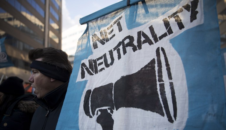 A demonstrator opposed to the roll back of net neutrality rules holds a sign outside the Federal Communications Commission headquarters ahead of an open commission meeting in Washington, D.C., on Thursday, Dec. 14, 2017.