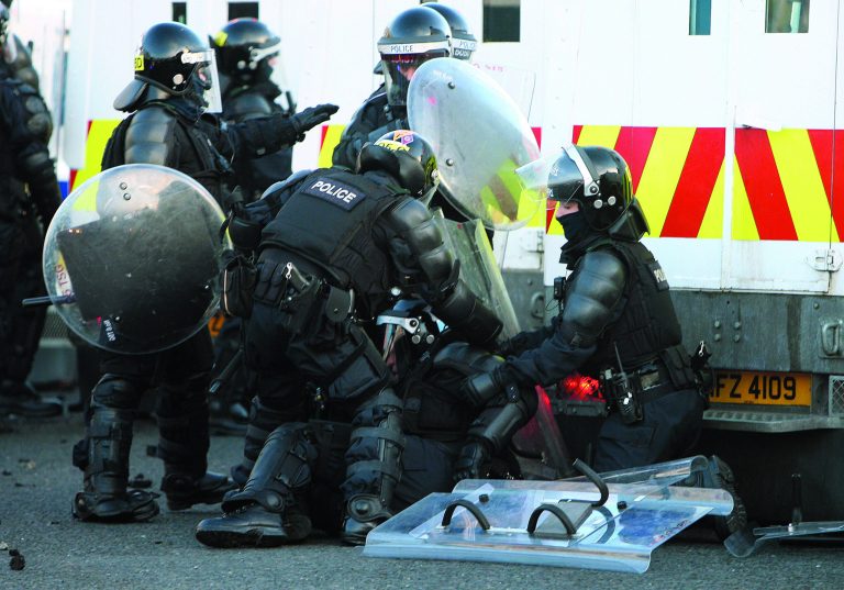 A police officer is injured after Loyalist protesters attacked police lines, at the Albertbridge Road near the nationalist Short Strand area of Belfast, Northern Ireland, Saturday Jan. 12, 2013. Police used water cannons as four officers were injured during sectarian clashes between loyalists and republicans in east Belfast, Saturday. Trouble flared after a city centre demonstration against the council's decision to limit the number of days the Union flag is flown from City Hall (AP Photo/Paul Faith/PA) UNITED KINGDOM OUT