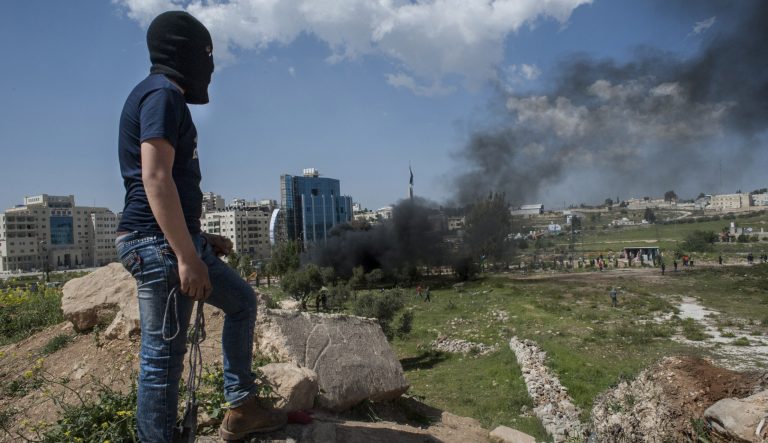 A young Palestinian protester overlooks clashes near Beit El, in Ramallah, West Bank, on Friday, April 6, 2018. 