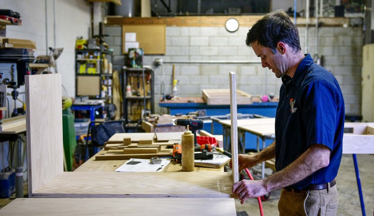 A worker glues pieces of wood together while making a kitchen cabinet at the Old Wood Co. sustainable furniture manufacturing facility in Asheville, N.C.