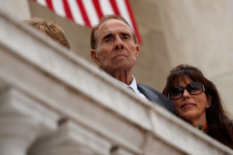Former Sen. Bob Dole watches as President Donald Trump speaks during a Memorial Day ceremony at Arlington National Cemetery, Monday, May 29, 2017, in Arlington, Va. (AP Photo/Evan Vucci)