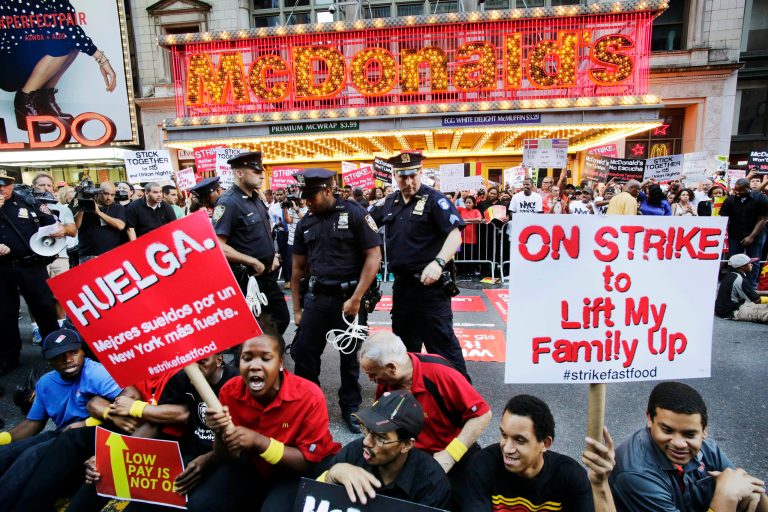 Protesters sit in front of a McDonald's restaurant on 42nd Street in New York's Times Square as police officers move in to begin making arrests, Thursday, Sept. 4, 2014. The protesters are seeking to get pay increases to $15 per hour. Thursday's demonstration is part of a day of planned protests in 150 cities across the country by workers from fast-food chains. (AP Photo/Mark Lennihan)