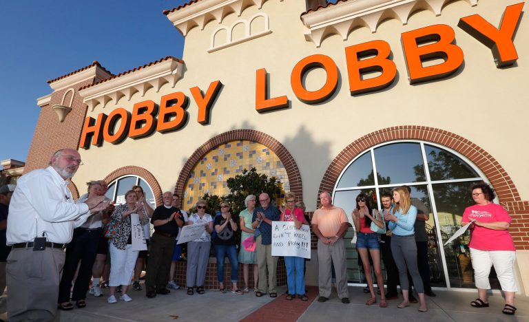 Rev. Bruce Prescott, left, applauds during a vigil outside a Hobby Lobby store in Edmond, Okla., Monday. (AP/Sue Ogrocki)