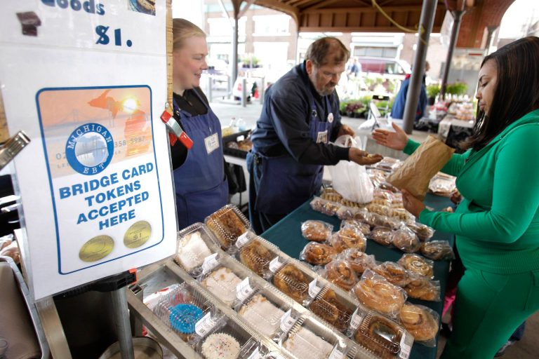 FILE - In this Sept. 11, 2010 file photo, Temeka Williams, right, of Detroit, uses her EBT/Bridge Card tokens for a purchase from Elizabeth and Gary Lauber from Sweet Delights at the Farmer's Market in Detroit. House approval of a scaled-back farm bill is setting up what could be an even bigger fight over food stamps and the role of domestic food aid in the United States. (AP Photo/Carlos Osorio, File)