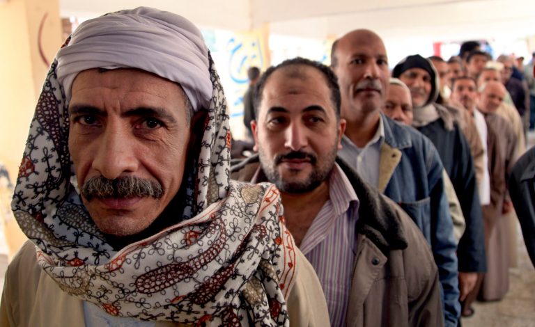   Egyptian men line up outside a polling station to cast their votes during a referendum on a disputed constitution drafted by Islamist supporters of President Morsi in Cairo, Egypt, Saturday, Dec. 15, 2012. (AP Photo/Khalil Hamra)  