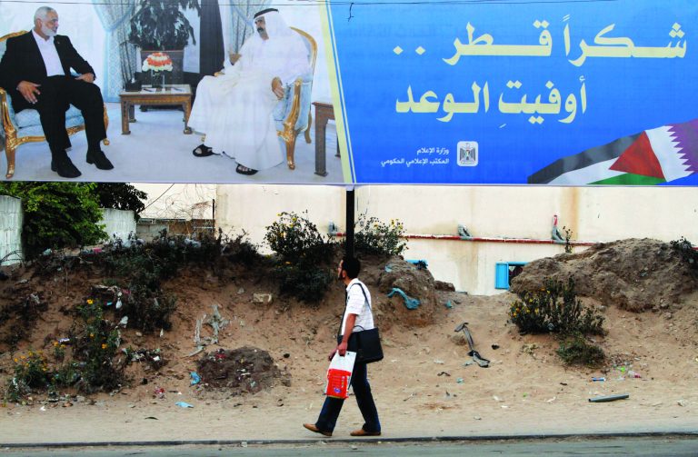 Palestinian youth walks near a poster of Gaza's Hamas Prime Minister Ismail Haniyeh, left, and Emir of Qatar Sheikh Hamad bin Khalifa al-Thani in Gaza City, Sunday, Oct. 21, 2012. The poster announces the coming visit of the Emir of Qatar, it reads, 