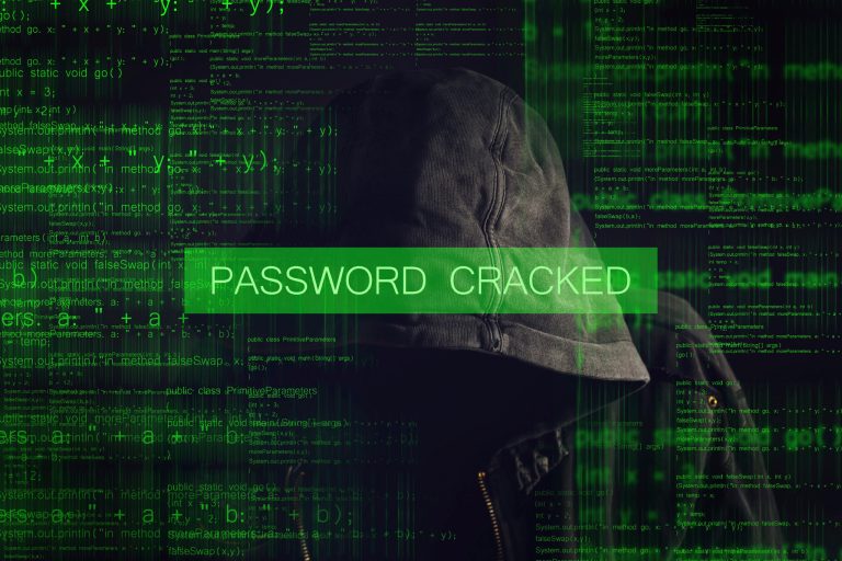 Password Cracked by Faceless hooded anonymous computer hacker with programming code from monitor