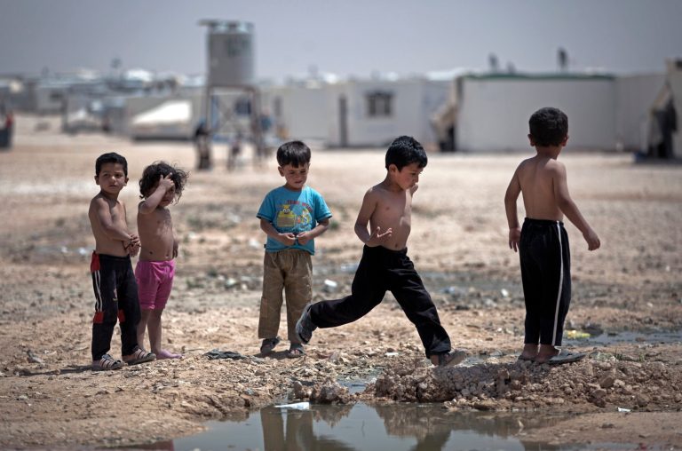 In this Thursday April 17, 2014 photo, Syrian children play under the heat of the midday sun at Zaatari refugee camp, near the Syrian border in Jordan. Life in this sprawling camp, Zaatari, is only getting harder for 130,000 residents, most of them fleeing fighting in south Syria. (AP Photo/Khalil Hamra)