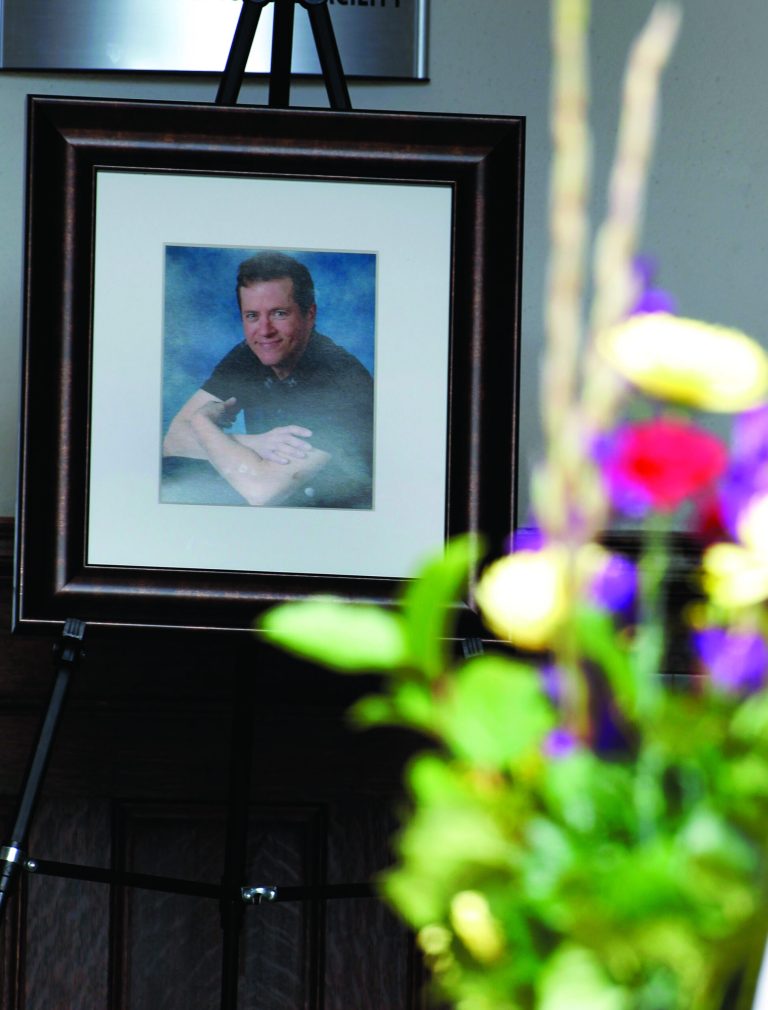 Flowers arrive as a portrait is seen at the entrance for at a memorial service for Gordon Cowden Wednesday, July 25, 2012 in Denver. Cowden was one of 12 people killed, and over 50 wounded in a shooting attack early Friday at the packed theater during a showing of the Batman movie, 