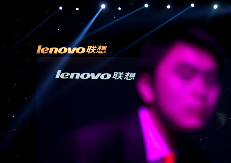 FILE - In this Aug. 6, 2012 file photo, a Lenovo employee, front, walks near the company logos during a Lenovo promotional event in Beijing, China. Lenovo said Thursday Jan. 23, 2014  it is acquiring IBM's x86 server business and expects to offer jobs to 7,500 IBM employees in locations around the world. (AP Photo/Alexander F. Yuan, File)