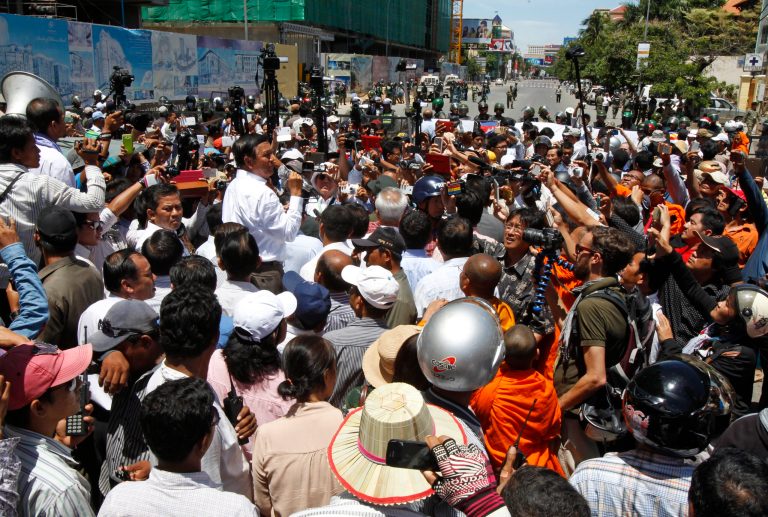 Cambodia's opposition deputy leader Kem Sokha,  center left, of the Cambodia National Rescue Party, gives a speech at a blocked main street near Phnom Penh Municipality Court in Phnom Penh, Cambodia, Wednesday, July 16, 2014. Five of lawmakers from the main opposition party of Cambodia National Rescue Party appeared in the court Wednesday for being questioned that they led about a hundred of their supporters Tuesday to demonstrate in front of the park, asking authorities to open the site to the public. (AP Photo/Heng Sinith)