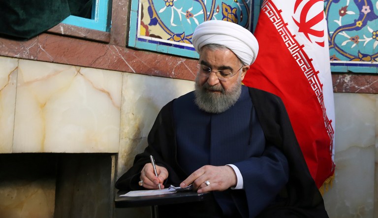 President Hassan Rouhani fills in his ballot while voting for the presidential and municipal councils election at a polling station in Tehran, Iran, Friday, May 19, 2017. (Iranian Presidency Office via AP)