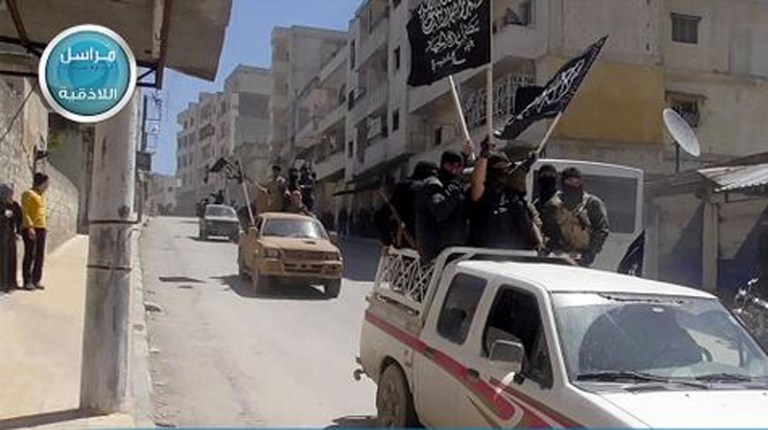 Al Nusra Front fighters wave their group's flags as they tour the streets of Jisr al-Shughour, Idlib province, Syria. (Al Nusra Front Twitter page via AP)