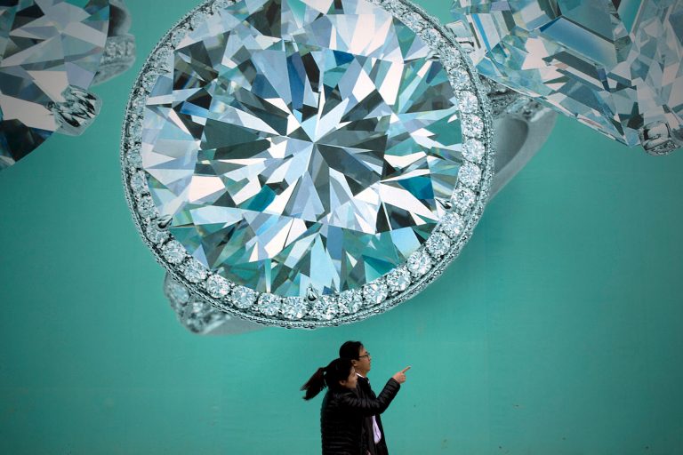FILE - In this Nov. 9, 2013 file photo, a Chinese couple walk past a billboard depicting diamonds at a commercial street in Beijing, China. Growth has marched steadily downward over the past two years as Beijing clamped down on a spending boom that analysts worry has pushed debt to dangerous levels. (AP Photo/Andy Wong, File)