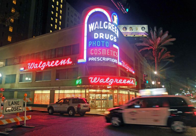 In this July 13, 2014 photo, a taxi speeds past the neon-lit Walgreens drugstore in the French Quarter of New Orleans. Walgreen reports quarterly financial results before the market opens on Tuesday, Sept. 30, 2014. (AP Photo/Rogelio V. Solis)