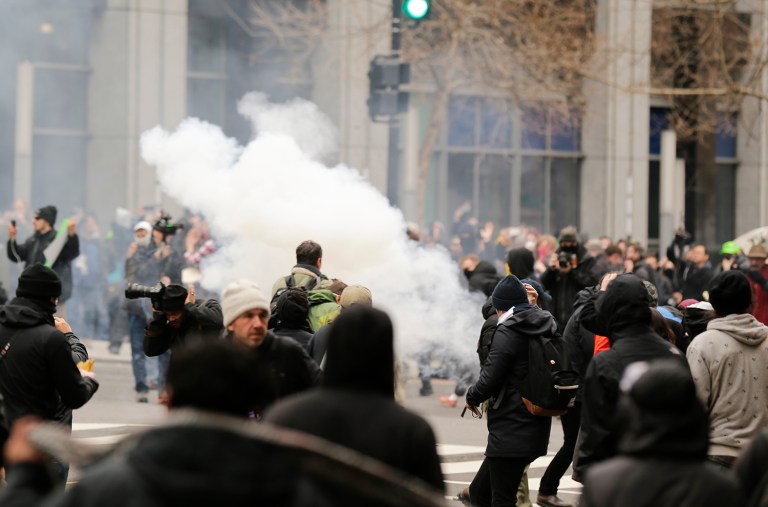 Police deploy smoke and pepper grenades during clashes with protesters in northwest Washington, Friday, Jan. 20, 2017. (AP Photo/Mark Tenally)