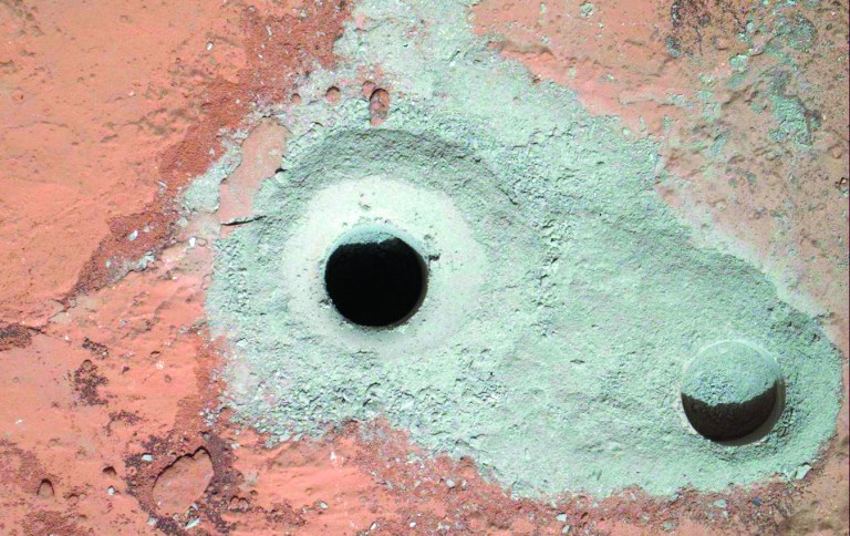 This image released by NASA on Saturday Feb. 9, 2013 shows a fresh drill hole, center, made by the Curiosity rover on Friday, Feb. 8, 2013 next to an earlier test hole. Curiosity has completed its first drill into a Martian rock, a huge milestone since landing in an ancient crater in August 2012. (AP Photo/NASA)
