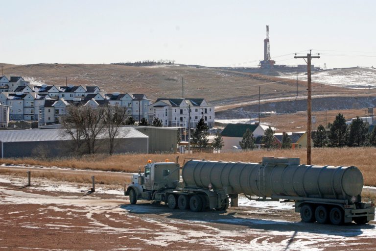 FILE - In this Feb. 26, 2014, file photo, an oil truck sits in a dirt lot near a new housing development in Watford City, N.D. The United States is still growing older, but the trend is reversing in the Great Plains, thanks to a liberal application of oil.  (AP Photo/Martha Irvine)